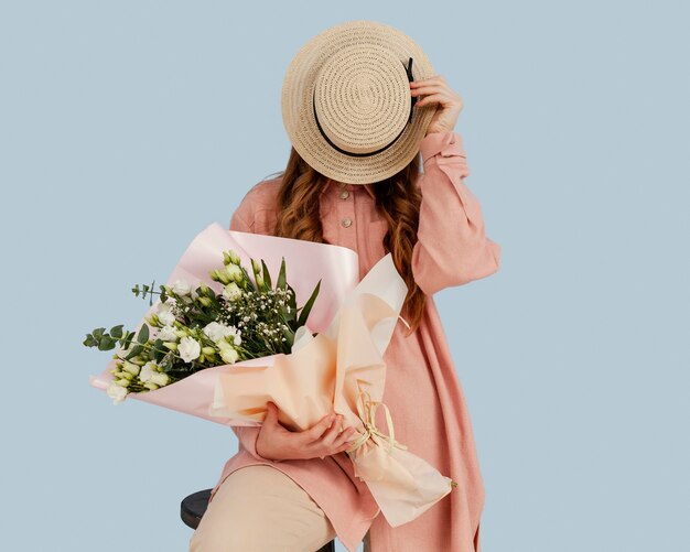 Front view of stylish woman posing with bouquet of spring flowers