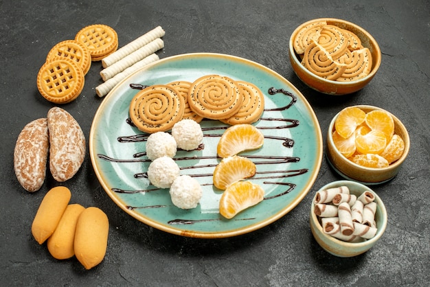 Foto gratuita biscotti di zucchero di vista frontale con caramelle e biscotti sul biscotto della torta della caramella della tabella grigia