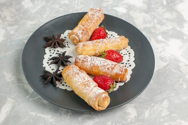 Front view of sugar powdered rolls with strawberries on white wall