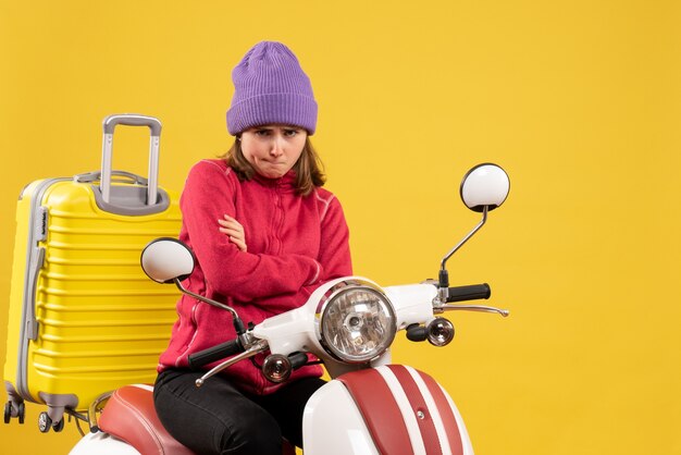 Front view sullen young woman on moped crossing hands