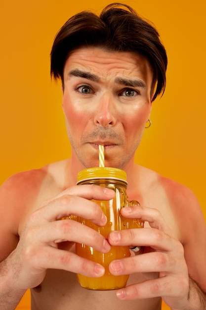 Front view sunburned man posing with drink