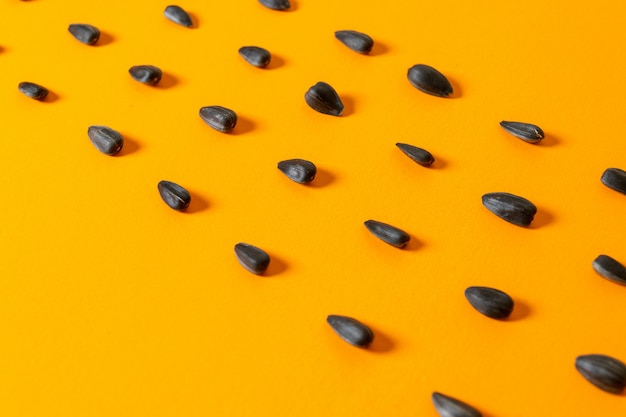 Семена подсолнечника, вид спереди, черные и жареные на желтом фоне