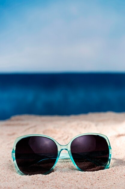 Front view of sunglasses on beach sand with copy space