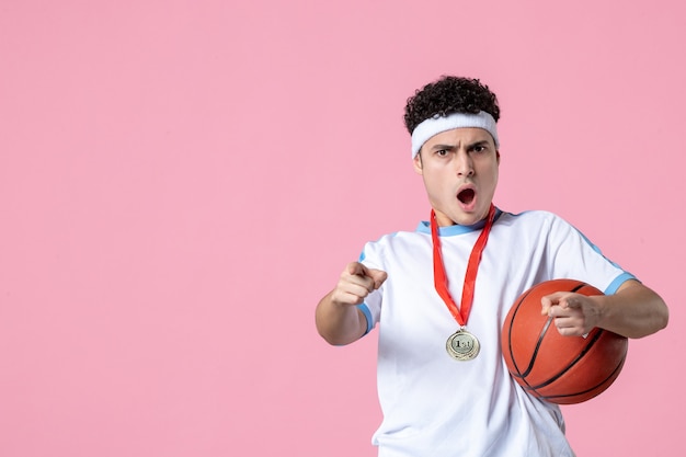 Free photo front view surprised basketball player holding ball with medal