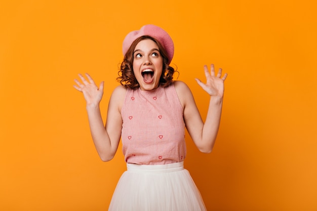 Free photo front view of surprised french girl. studio shot of amazed elegant woman in beret isolated on yellow background.