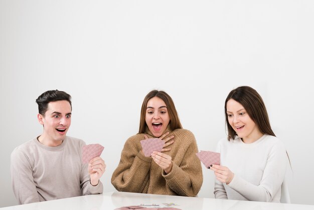 Front view surprised friends playing cards game