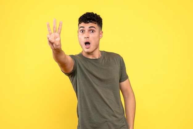 Front view of surprised guy shows three fingers