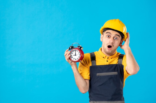 Free photo front view of surprised male worker in uniform with clocks on blue
