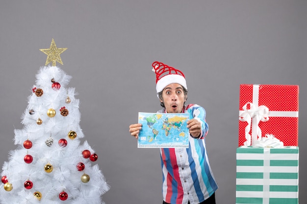 Free photo front view surprised man with spiral spring santa hat showing world map