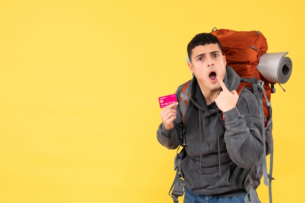 Front view surprised traveler man with red backpack holding credit card