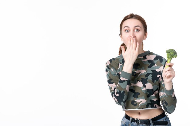 Front view surprised young female holding little green broccoli on white background lunch meal salad dish healthcare diet food health human