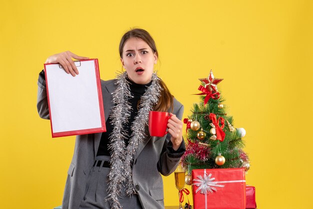 Front view surprised young girl holding document and red cup