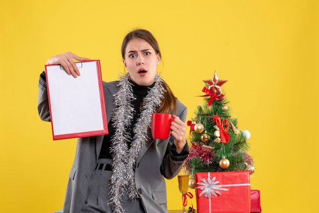 Front view surprised young girl holding document and red cup