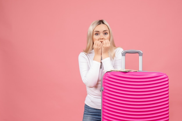 Front view surprised young lady standing behind big suitcase