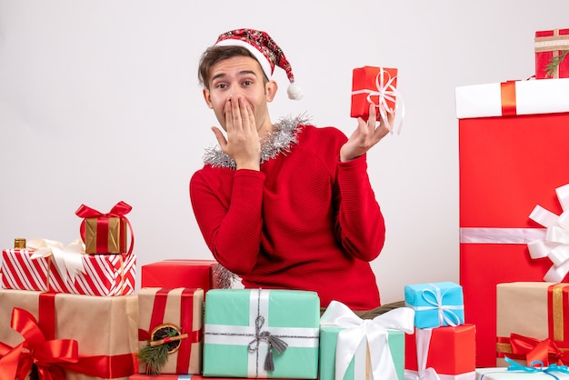 Front view surprised young man sitting around xmas gifts