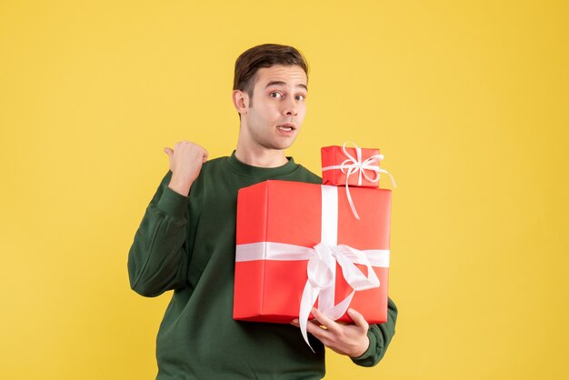 Front view surprised young man with xmas gift standing on yellow 