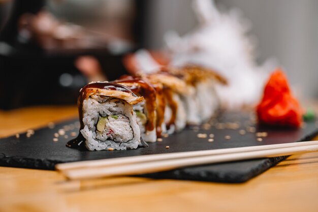 Front view sushi rolls with eel and sauce on a stand