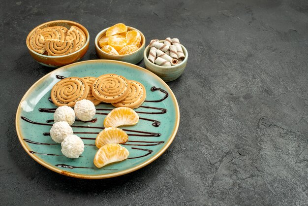 Front view sweet biscuits with coconut candies on a grey desk biscuit cookie sweet