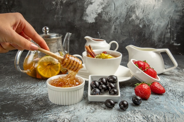 暗い床の朝の食べ物の朝食にお茶とオリーブと甘い蜂蜜の正面図