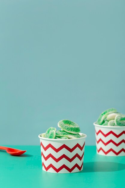 Free photo front view of sweet jelly in cups with spoon and copy space