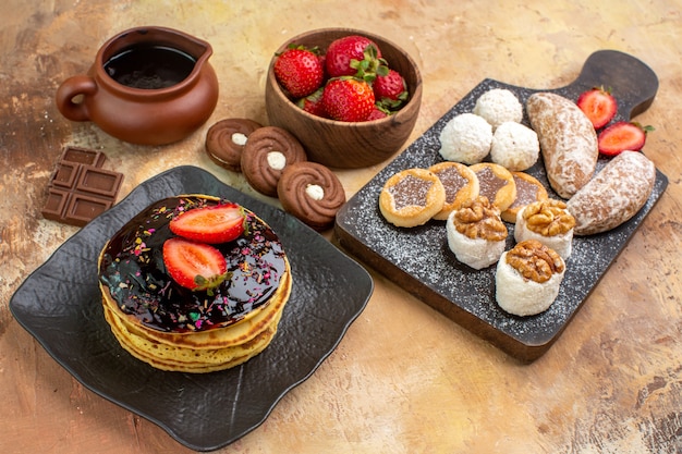 Front view sweet pancakes with cakes and cookies on wooden desk