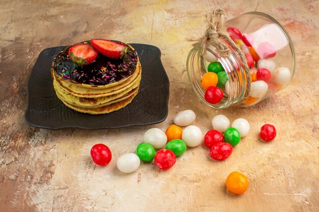 Вид спереди сладкие блины с красочными конфетами на деревянном столе