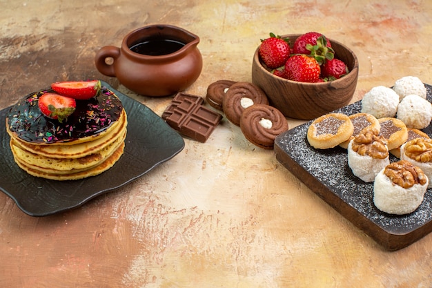 Front view sweet pancakes with sweets and cookies on wooden desk cake pie sweet dessert