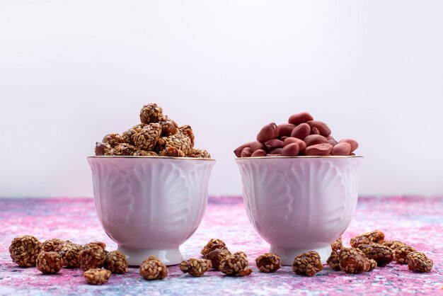 Front view sweet sticky nuts inside purple plates