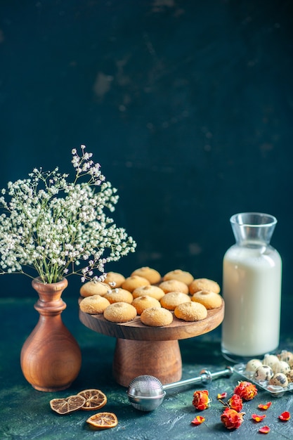 Vista frontale dolci deliziosi biscotti con latte e noci sulla superficie blu scuro