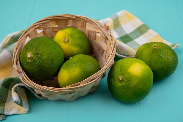 Front view tangerines in a basket with a checkered towel on a blue wall