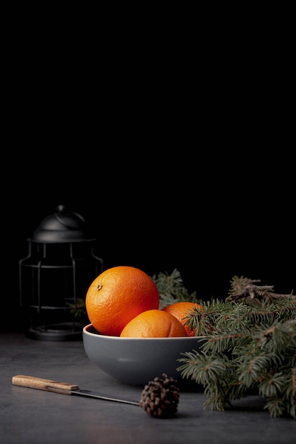 Front view of tangerines in bowl with pine and copy space