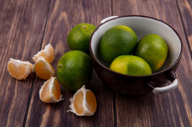 Front view tangerines in a saucepan on a wooden wall