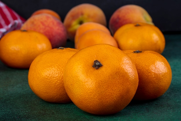 Front view tangerines with peaches on green