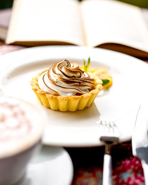 Front view tartlet with meringue and an open book on the table