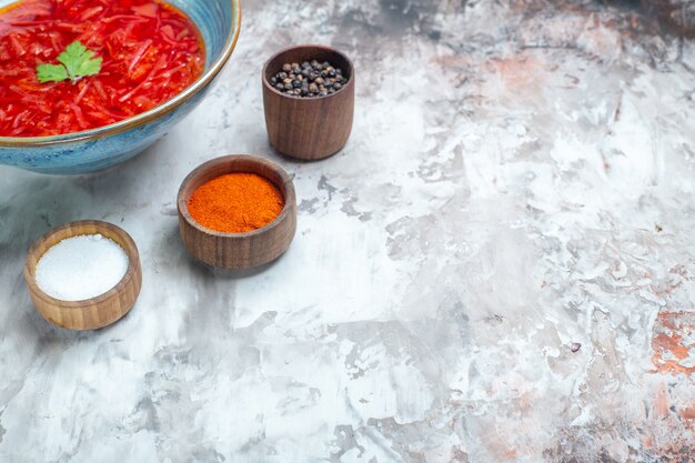 흰색 테이블에 조미료를 넣은 맛있는 보르쉬 우크라이나 비트 수프 전면 보기