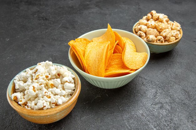 Вид спереди вкусные сырные чипсы с разными закусками на темном фоне