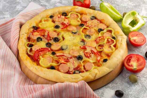 Front view tasty cheesy pizza with black olives sausages and red tomatoes on grey d