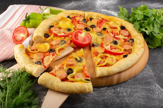 Вид спереди вкусная сырная пицца с красными помидорами, черными оливками, болгарским перцем и сосисками, нарезанными на сером