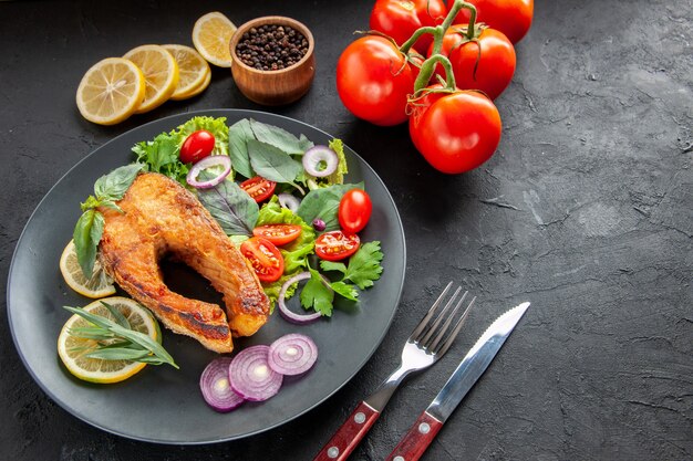 Вид спереди вкусная приготовленная рыба со свежими овощами и столовыми приборами на темном фоне цветная еда фото блюдо мясо морепродукты сырые