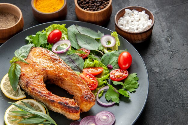 Front view tasty cooked fish with fresh vegetables and seasonings on dark background color food meat seafood dish photo