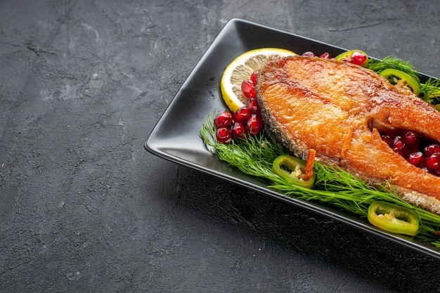 Front view tasty cooked fish with greens and lemon slices inside pan on a dark background color fruit seafood food dish photo meat