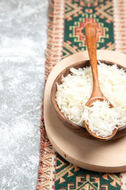Вид спереди вкусный вареный рис внутри коричневой тарелки на белом пространстве