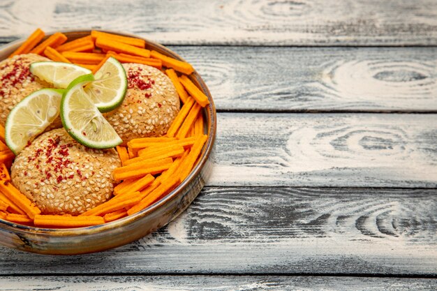 Front view tasty cookies with lemon slices and rusks on the rustic grey desk