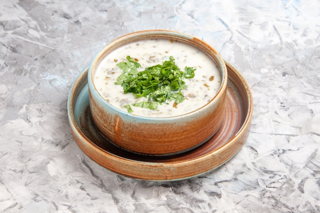 흰색 테이블 우유 수프 식사 접시에 채소를 곁들인 맛있는 도브가 요구르트 수프 전면 보기