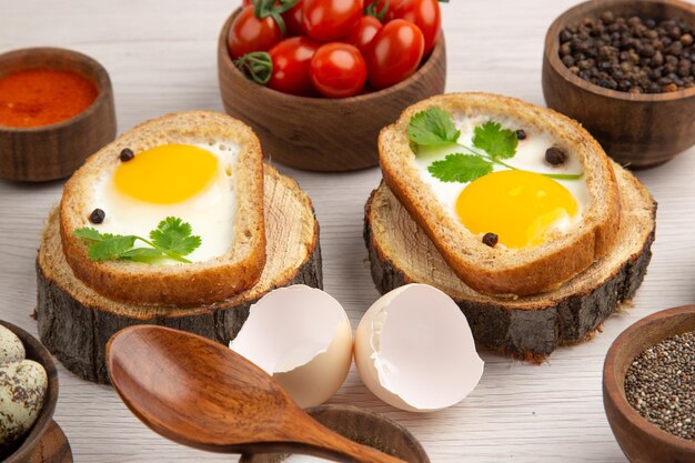 Вид спереди вкусные яичные тосты с приправами и помидорами на белом фоне фото утренняя еда цвет завтрак еда обед салат