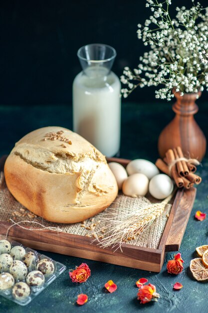 Вид спереди вкусный свежий хлеб с яйцами и молоком на темной поверхности