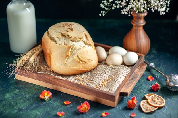 Вид спереди вкусный свежий хлеб с яйцами и молоком на темной поверхности