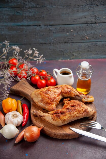 Вид спереди вкусный жареный цыпленок со свежими овощами и приправами на темном пространстве