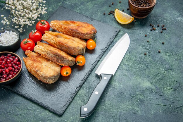 Вид спереди вкусная жареная рыба с помидорами на темно-синей поверхности морепродукты салат еда мясо морепродукты приготовление жареного блюда