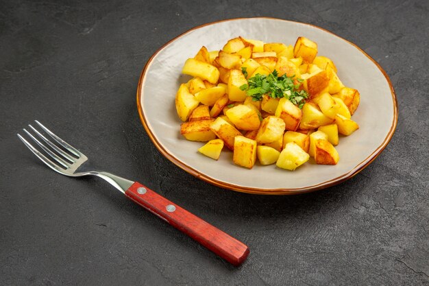 Free photo front view tasty fried potatoes inside plate with greens on dark table